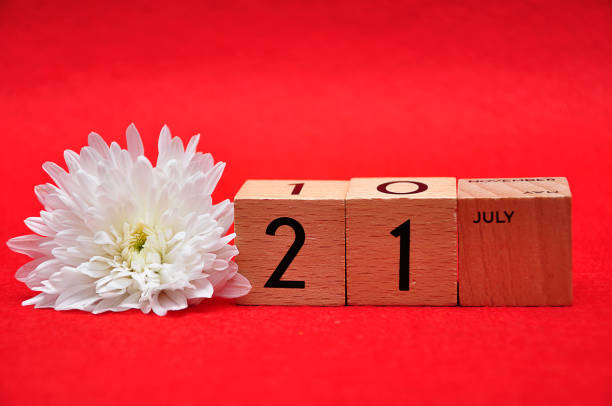 istock 21 July on wooden blocks with a white daisy on a red background 1145631208