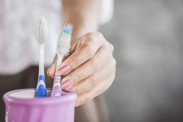 Photo of woman hand using old and destroy toothbrush closeup