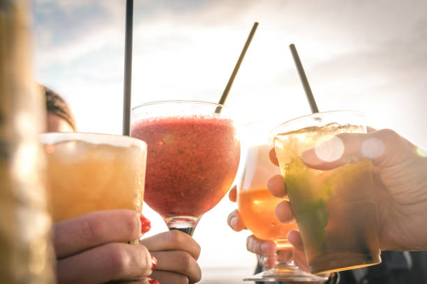 最高の友人に挨拶, 友人のグループ日没のビーチで夕方の飲み物を楽しんで.休暇、屈託のない、一日の終わりのリラクゼーション、お祝いと幸福の概念。 - summer cocktail ストックフォトと画像