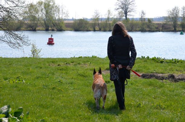 Well, Holland - 04/14/2019: Woman and her dog slowly walk to the river while enjoying the view