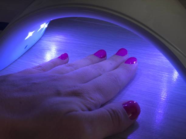 istock Hand with painted nails dried in an ultraviolet lamp. Manicure process. Hand care 1145639268