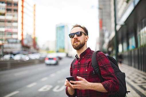Hombre adulto joven en busca de un taxi en la aplicación móvil photo