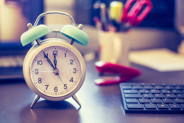istock Alarm clock is standing on a grey desk, office stuff in the blurry background 1145639880