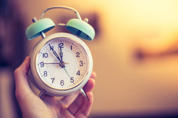 istock Man is holding an alarm clock in the hand, blurry background 1145639907