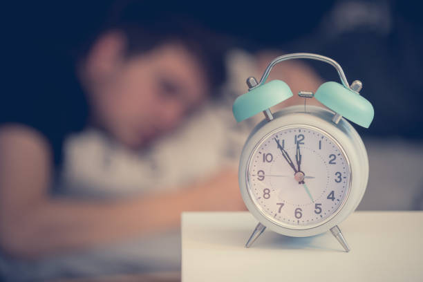 朝の目覚まし時計。若い男はぼやけた背景に眠る。 - uprise ストックフォトと画像