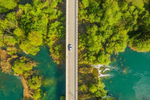 istock Car crossing road bridge over wild river 1145642942