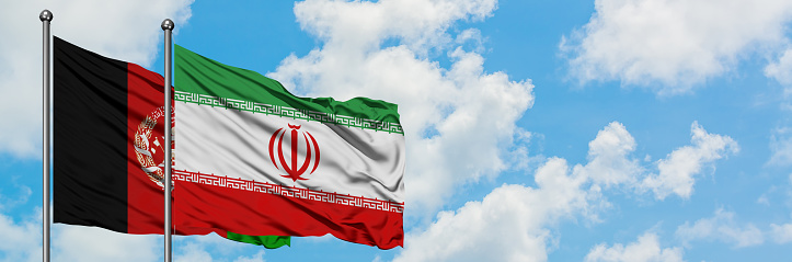 Afghanistan and Iran flag waving in the wind against white cloudy blue sky together. Diplomacy concept, international relations.