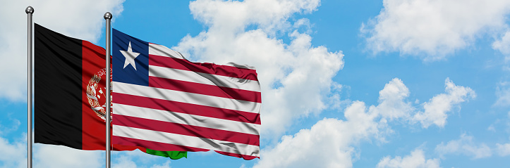 Afghanistan and Liberia flag waving in the wind against white cloudy blue sky together. Diplomacy concept, international relations.