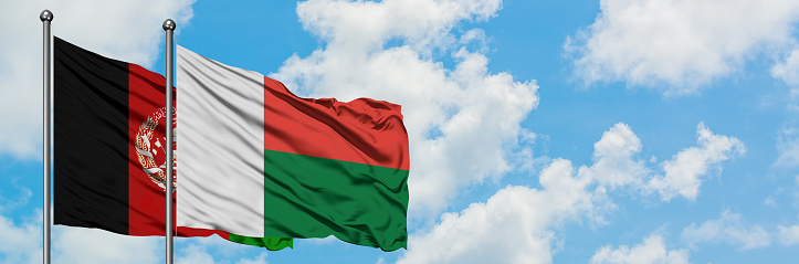 Afghanistan and Madagascar flag waving in the wind against white cloudy blue sky together. Diplomacy concept, international relations.