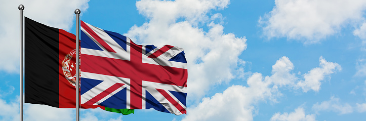 Afghanistan and United Kingdom flag waving in the wind against white cloudy blue sky together. Diplomacy concept, international relations.