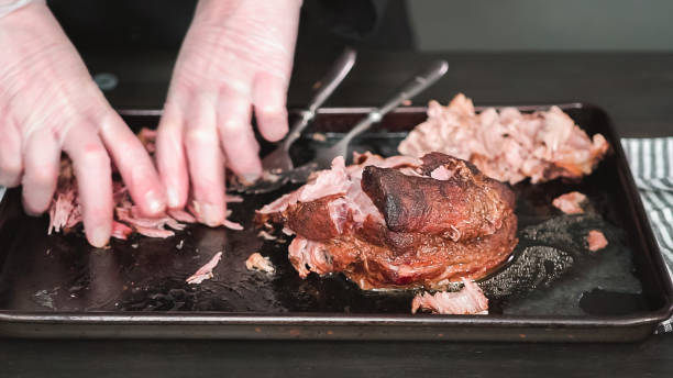 istock Shredding pork roast shoulder with two forks. 1145648547