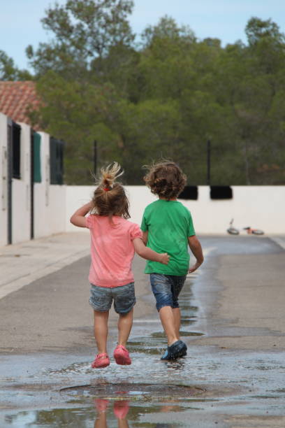 istock Children playing outside in a puddle of water 1145648876
