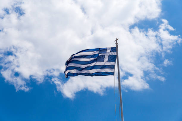 istock greek flag waving on blue sky clouds greece background 1145651323