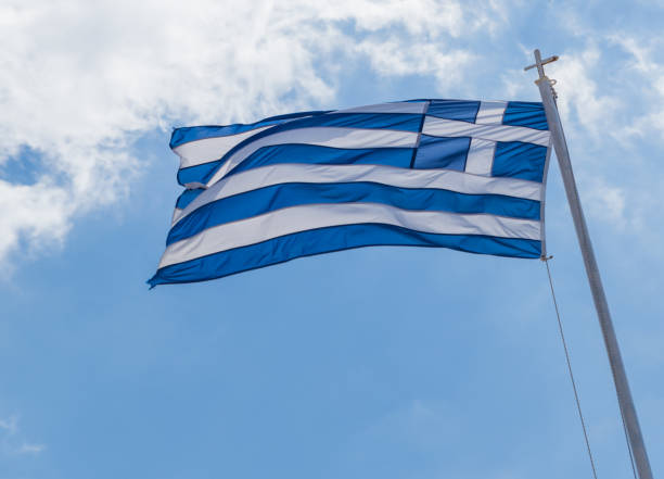 istock greek flag waving on blue sky clouds greece background 1145651910