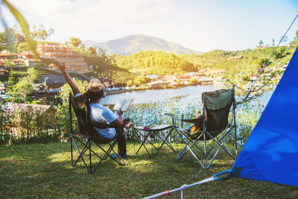 istock Asian men tourists camping and And working notebook, She is happy, relaxed, enjoying reading a book, Travel nature, Travel relax. 1145654126