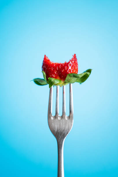 Ripe Strawberry on silver fork against blue background
