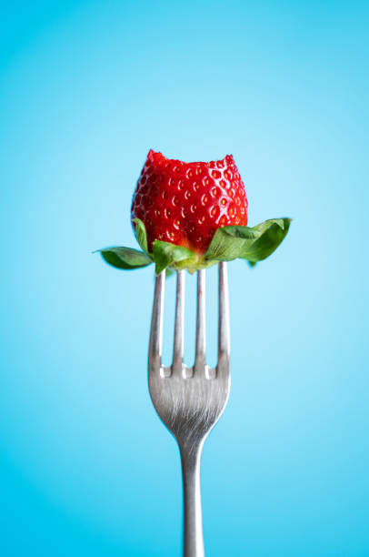 istock Ripe Strawberry on silver fork against blue background 1145654420