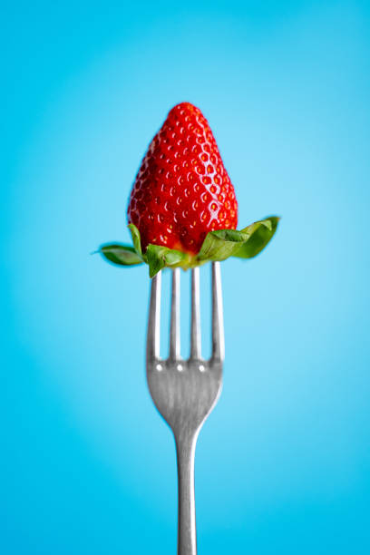 istock Ripe Strawberry on silver fork against blue background 1145654423