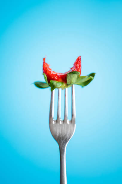 istock Ripe Strawberry on silver fork against blue background 1145654424