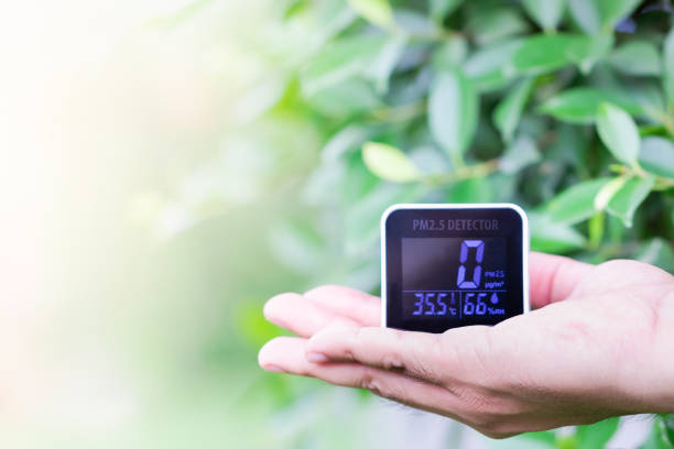 istock People hand holding PM 2.5 detector checking dust on blurred green leaf. 1145654623
