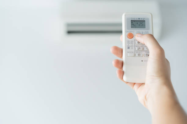istock Woman hand using remote control open air conditioning 25 degrees. Open air 25 degrees, is temperature, save energy 1145654693