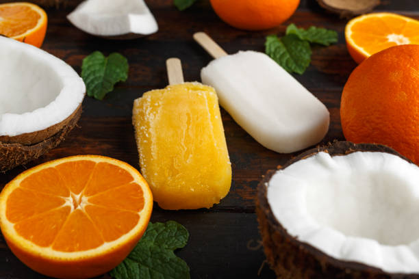 Homemade Coconut, Orange popsicles, ice lolly, on wooden table. Summer food.