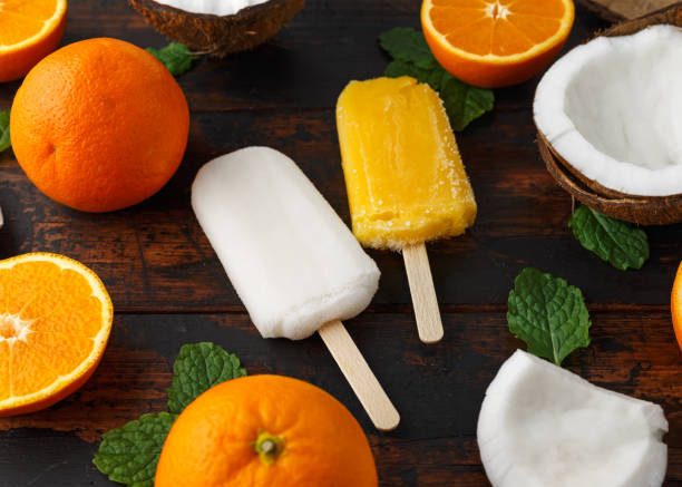 Homemade Coconut, Orange popsicles, ice lolly, on wooden table. Summer food.