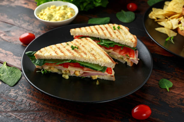 ハム、チーズ、トマト、ほうれん草、トウモロコシ、マヨネーズ、マスタード、ガーキン、トーストとポテトチップスを焼くサンドイッチ。 - club sandwich sandwich salad bread ストックフォトと画像