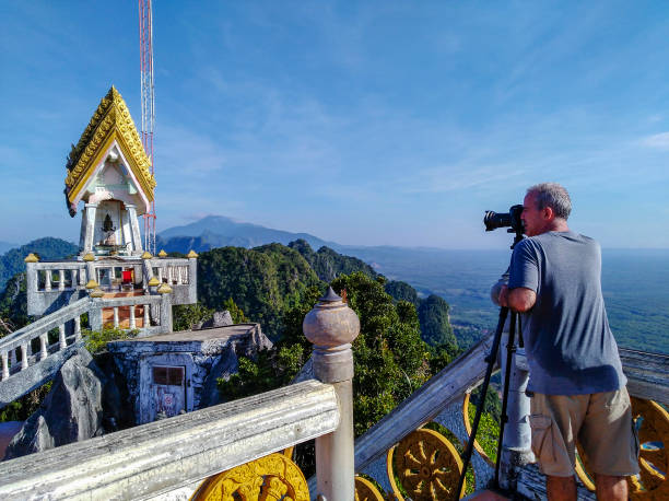 Adult Man Tourist Photographer One adult man photographer on vacation taking a tourist travel destination photograph at a Thai temple called Wat Tham Sua located on top of a limestone karst in the town of Krabi located in Krabi Province, Thailand. wat tham sua stock pictures, royalty-free photos & images