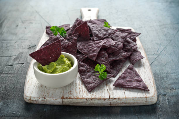 istock Blue corn Organic tortilla chips with Guacamole on white wooden board 1145658308