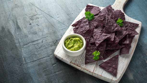istock Blue corn Organic tortilla chips with Guacamole on white wooden board 1145658382