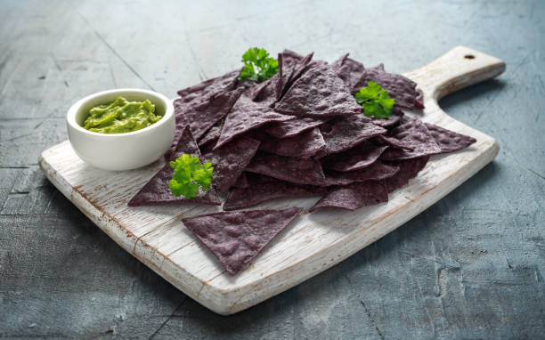 istock Blue corn Organic tortilla chips with Guacamole on white wooden board 1145658401
