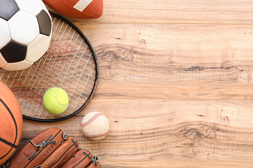 Various sports equipment, balls on wooden background.