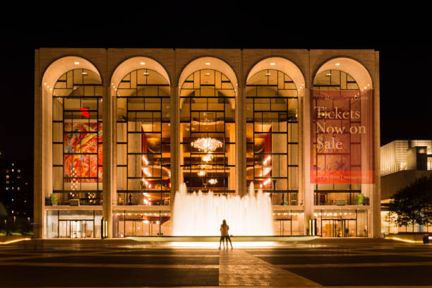 Night view of the Metropolitan Opera House in the Lincoln Center at Upper West Side Manhattan, New York City, USA. Night view of the Metropolitan Opera House in the Lincoln Center at Upper West Side Manhattan, New York City, USA. The Lincoln Center is the most important cultural complex in New York city. A couple is sitting next to the water fountain. dancing school stock pictures, royalty-free photos & images