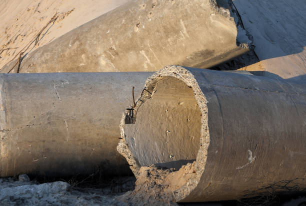 Concrete pipes (tubes) near the sand pile in the construction site.