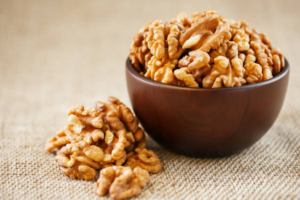 istock Peeled walnuts in a wooden, dark brown cup on a burlap cloth. 1145666856