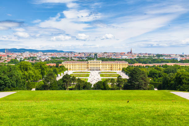 Schönbrunn Palace in Vienna seen from the public gardens with fountains and dark clouds above during an overcast day in spring.