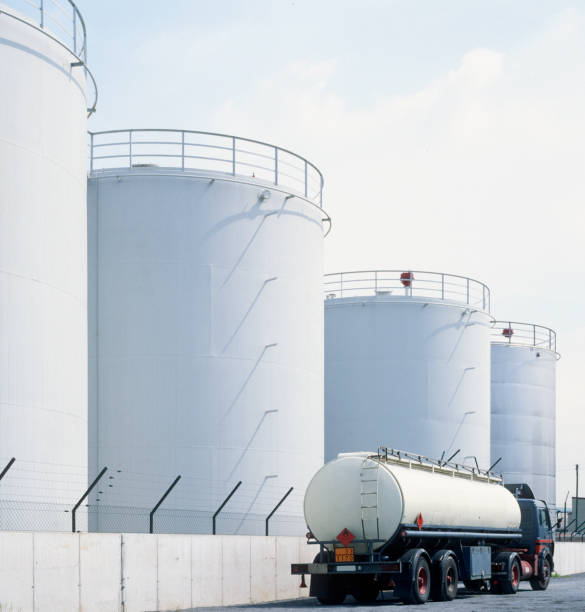 road tanker and oil tanks road tanker in front of oil refinery tanks, neutral with copy space fuel storage tank photos stock pictures, royalty-free photos & images