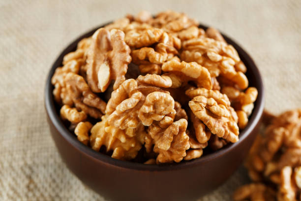 istock Peeled walnuts in a wooden, dark brown cup on a burlap cloth. 1145672221