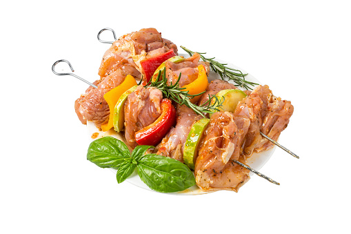 skewers of raw meat and vegetables in marinade on the plate isolated on white background. grill barbeque