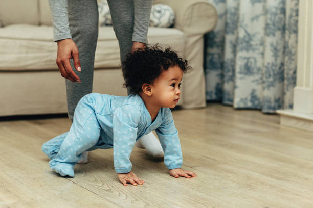 istock Side view of cute baby boy crawling on floor at home 1145683071