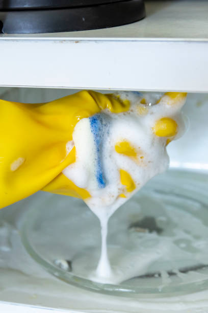 Person in gloves cleaning microwave oven, closeup