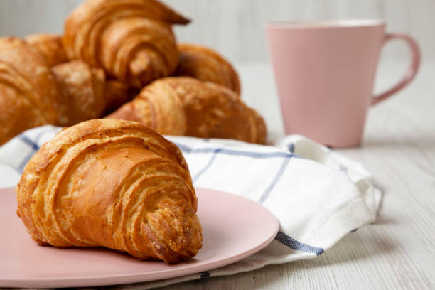 istock Fresh croissant on a pink plate, side view. Close-up. 1145688834