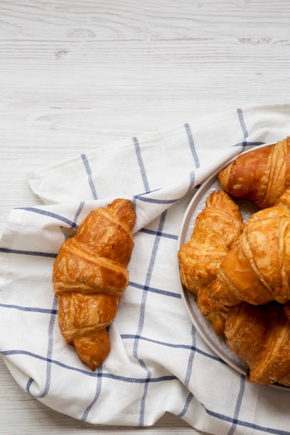 istock Fresh croissants on a white wooden surface, top view. From above, overhead, flat lay. Copy space. 1145689783