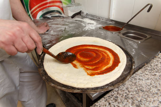 istock The chif pouring tomato sauce by ladle on a pizza 1145692519