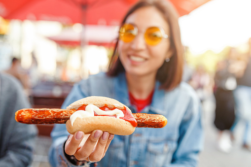 Woman eating Currywurst fast food German sausage in outdoor street food cafe