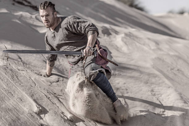 eine individuelle wikinger-krieger in aktion auf einer sandigen schlachtfeld düne - petrified sand dune stock-fotos und bilder