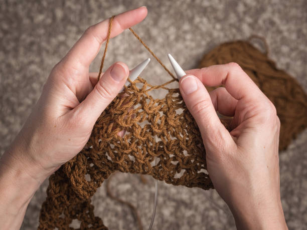 hands knitting with brown yarn stock photo