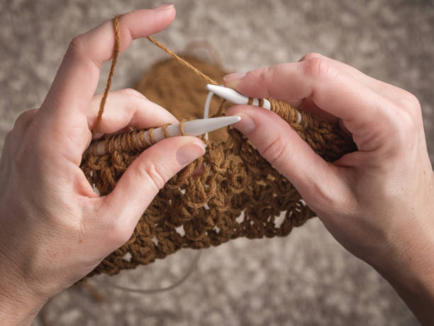 hands knitting with brown yarn stock photo