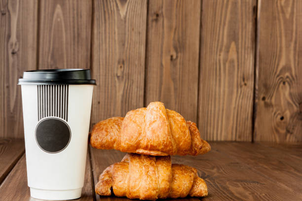 istock Paper coffee cup and croissants on wooden background, Copy space 1145704976